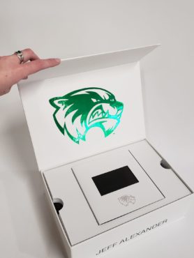 An opened UVU custom marketing box showcasing the foil logo and the small video screen.